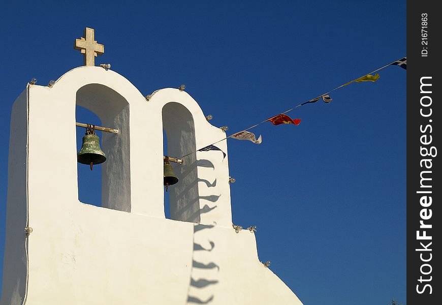 Bell Tower, Cross and Flags Against Blue Sky in Santorini, Greece. Bell Tower, Cross and Flags Against Blue Sky in Santorini, Greece