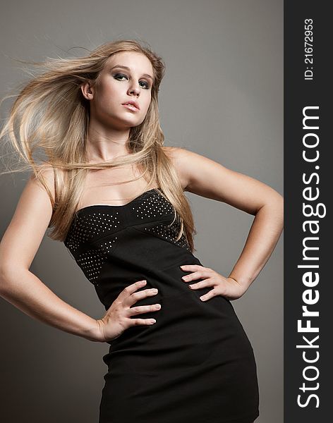 Portrait of young posing fashionable woman with smart fair hair in black dress. Studio shot. Portrait of young posing fashionable woman with smart fair hair in black dress. Studio shot.
