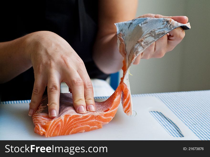 A chef removing skin from a piece of salmon in preparation for cooking. A chef removing skin from a piece of salmon in preparation for cooking.
