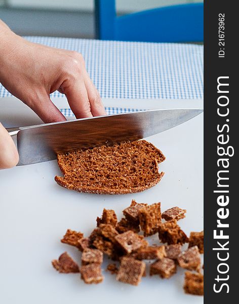 A chef cutting a piece of rye bread for croutons in preparation for cooking. A chef cutting a piece of rye bread for croutons in preparation for cooking.