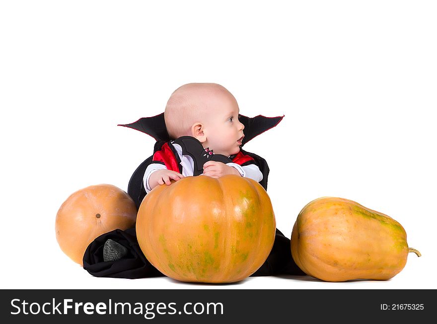 Little baby boy sitting in black halloween cloak near pumpkins. Little baby boy sitting in black halloween cloak near pumpkins