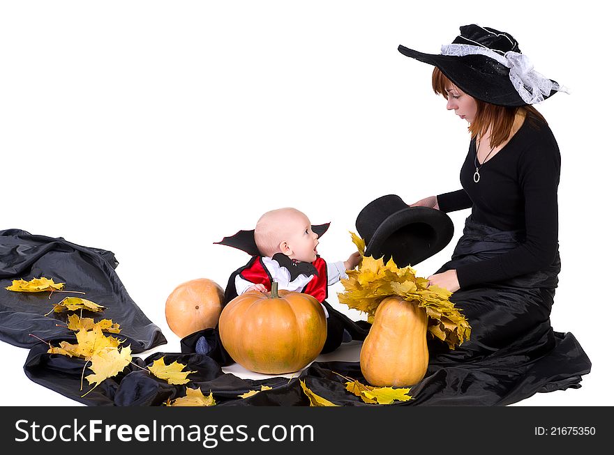 Little halloween baby boy playing with mother witch near pumpkings among yellow leaves. Little halloween baby boy playing with mother witch near pumpkings among yellow leaves