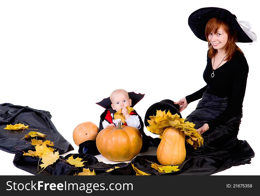 Little halloween baby boy playing with mother witch near pumpkings among yellow leaves and smiling. Little halloween baby boy playing with mother witch near pumpkings among yellow leaves and smiling