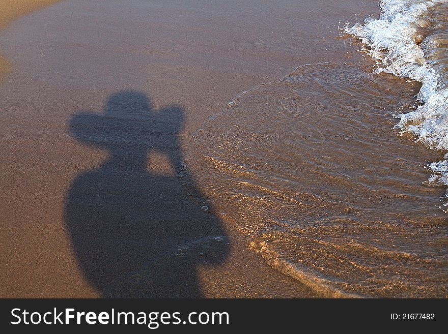 Shadow of man in hat on the sandy beach. Shadow of man in hat on the sandy beach.