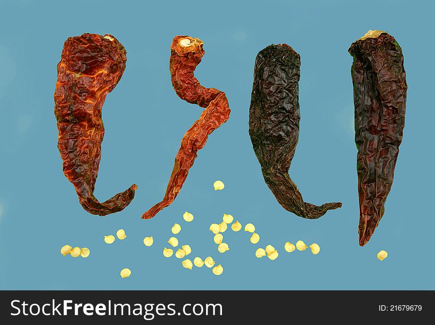 Four isolated dried red Kashmiri chillies with scattered isolated and grouped chilli seeds. Four isolated dried red Kashmiri chillies with scattered isolated and grouped chilli seeds.