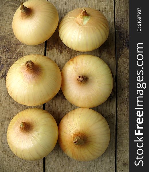 six onions on a wooden background closeup