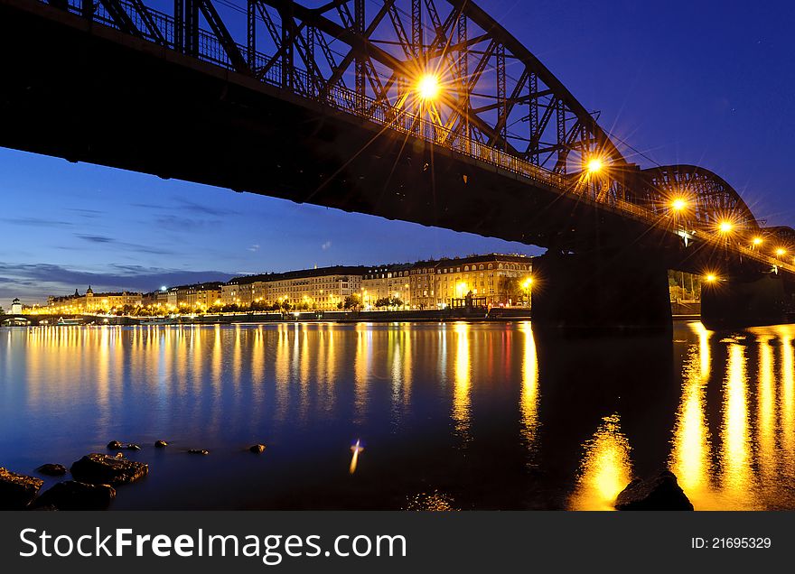 Railroad bridge over the river in the city after sunset