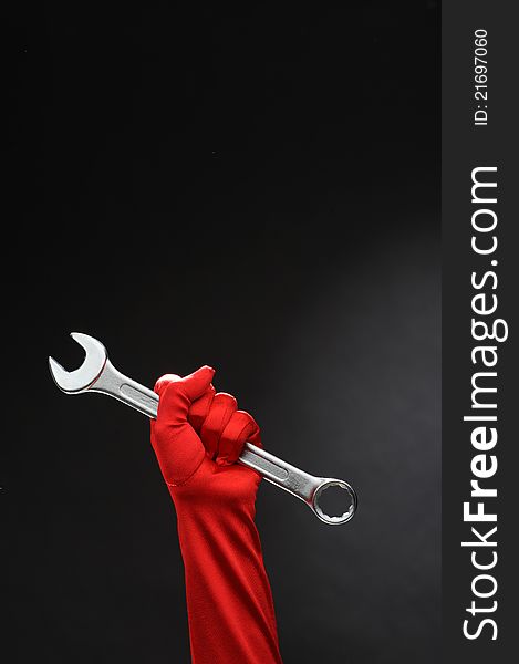 Big spanner in the woman's hand with red glove. Big spanner in the woman's hand with red glove