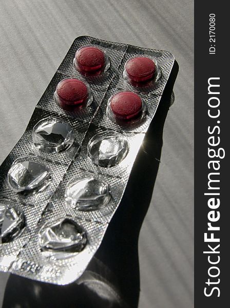 Four red pills isolated in an aluminium package