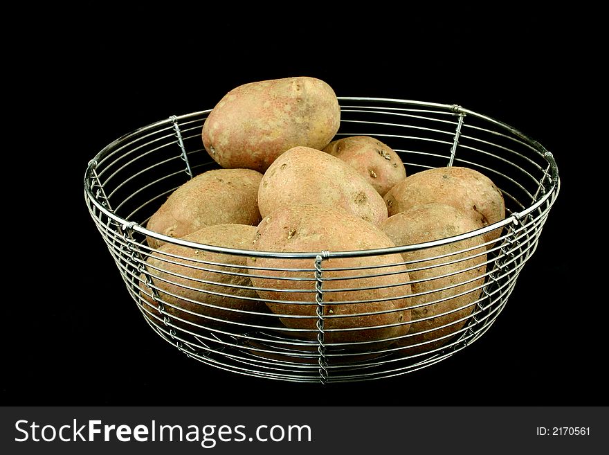 Some red potatoes put in a wire bowl on the black backround. Some red potatoes put in a wire bowl on the black backround