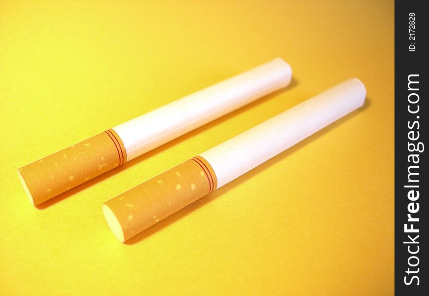 Two cigarettes on a yellow background