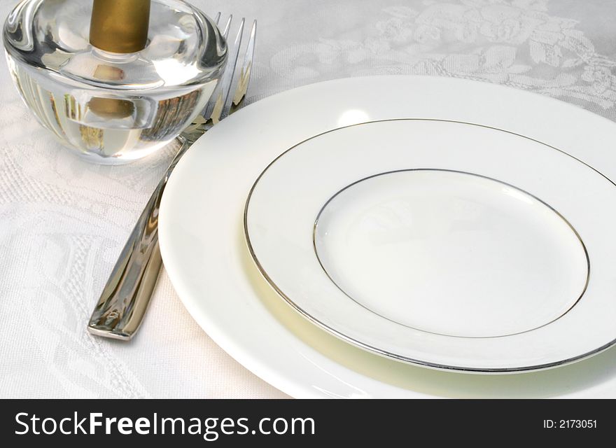 Table set for dinner with a white plate and table cloth (blur added to soften details). Table set for dinner with a white plate and table cloth (blur added to soften details)