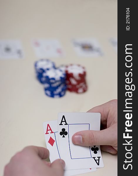 Man playing poker has two aces while playing poker with gambling chips on the table. Man playing poker has two aces while playing poker with gambling chips on the table