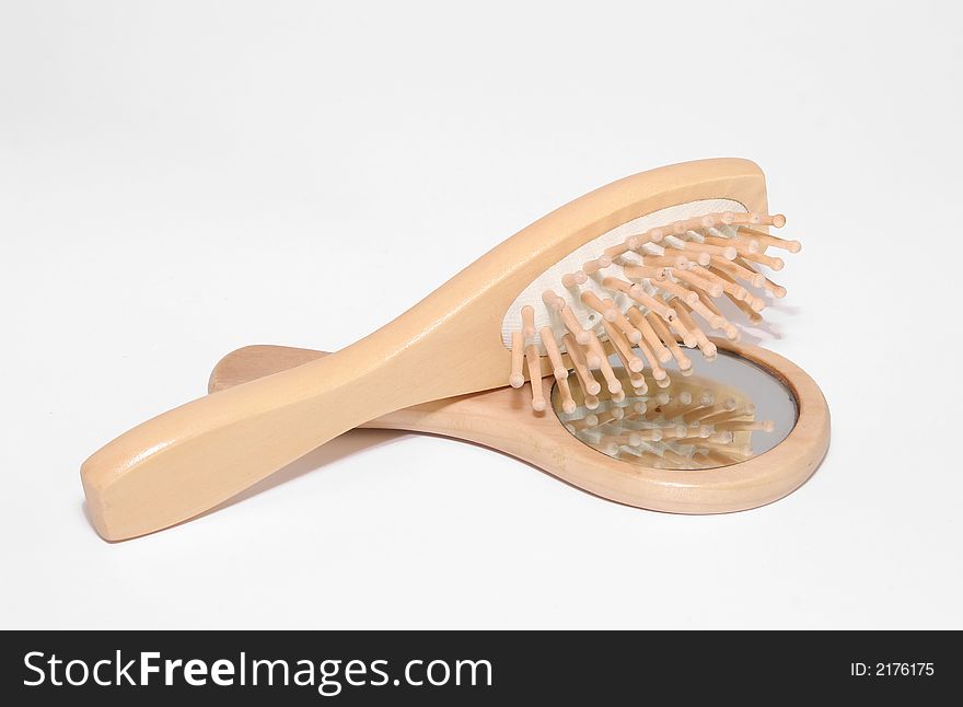 A wooden hairbrush and mirror set on a white bakground. A wooden hairbrush and mirror set on a white bakground