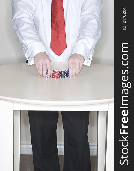Man standing at a table holding some gambling chips in his hands. Man standing at a table holding some gambling chips in his hands