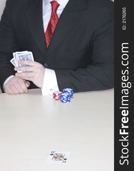 Man holding a hand of poker cards while sitting at a table playing poker. Man holding a hand of poker cards while sitting at a table playing poker