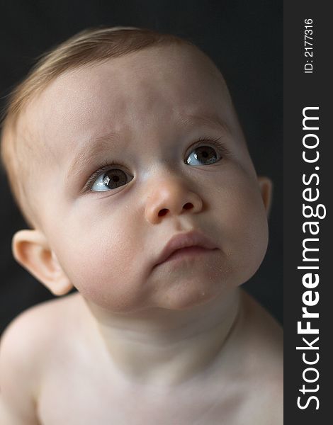 Image of beautiful 10 month old baby boy sitting in front of a black background. Image of beautiful 10 month old baby boy sitting in front of a black background
