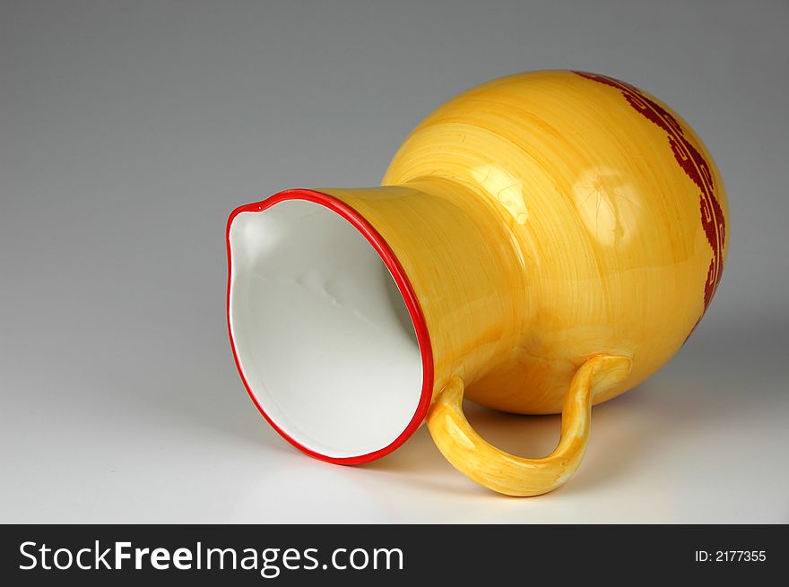 Ceramic jug in yellow and red on neutral background