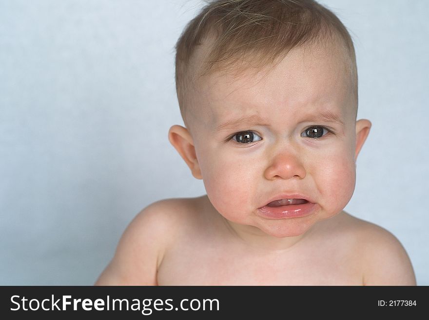 Image of cute whining baby sitting in front of a white background. Image of cute whining baby sitting in front of a white background