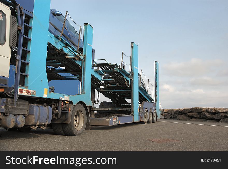 A semi truck car transporter parked up with 2 cars onboard.