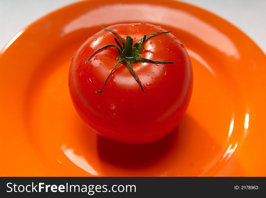 Red tomato on orange plate
