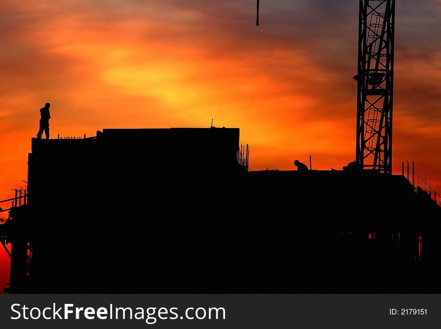 Beautiful sky at sunrise in city. Building under construction and workers at top of the building. Beautiful sky at sunrise in city. Building under construction and workers at top of the building.