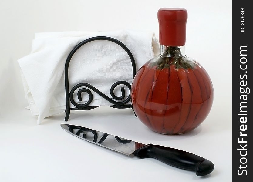 Still life of knife, cloth napkins, and bottle of red chillis, isolated on white. Still life of knife, cloth napkins, and bottle of red chillis, isolated on white.