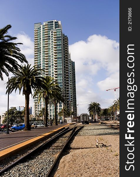 Train leaving station, with high-rise luxury condos and palm trees in the background. Train leaving station, with high-rise luxury condos and palm trees in the background