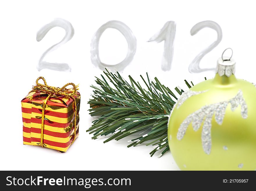 Christmas green ball, red and yellow striped box and spruce  branch on 2012 background. Christmas green ball, red and yellow striped box and spruce  branch on 2012 background