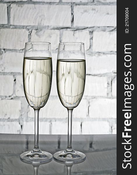 Two wineglasses of champagne over colored background