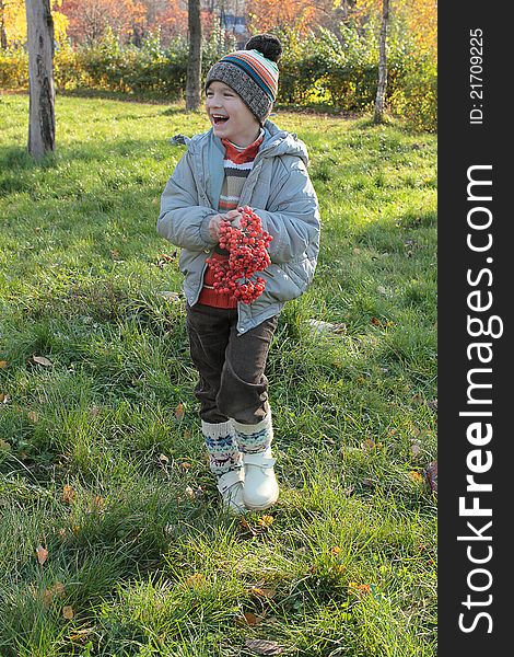 Laughing boy in autumn park with rowan berries. Laughing boy in autumn park with rowan berries.