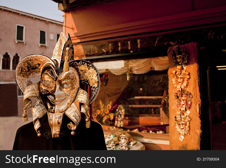 Doll portrait with vemetian gold black and white mask and beautifull shop behind the doll, Venice, Italy. Doll portrait with vemetian gold black and white mask and beautifull shop behind the doll, Venice, Italy