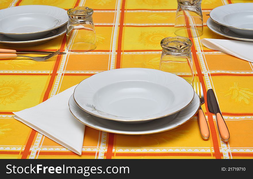 Dressed table for three with orange table cloth. Dressed table for three with orange table cloth