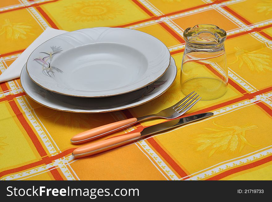 Dressed table for three with orange table cloth. Dressed table for three with orange table cloth