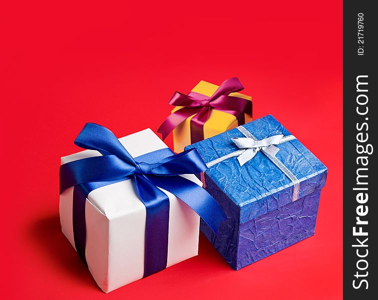 Three boxes with gifts on red background.