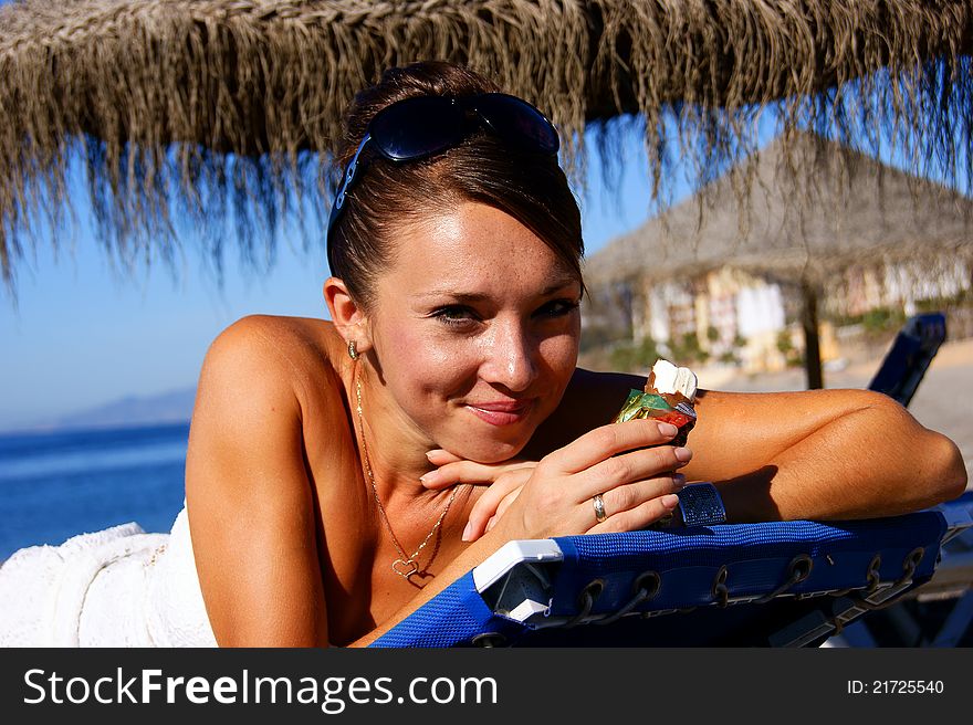 The girl lies on a plank bed and eats ice-cream. The girl lies on a plank bed and eats ice-cream