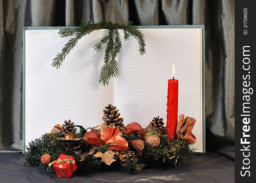 Blank pages of old open notebook bordering with christmas decoration and red burn candle. Blank pages of old open notebook bordering with christmas decoration and red burn candle