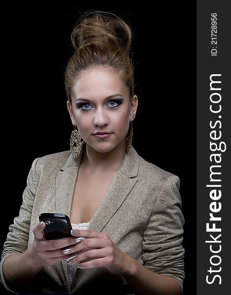 Young business woman with blue eyes, mobile phone, earrings and black background. Young business woman with blue eyes, mobile phone, earrings and black background