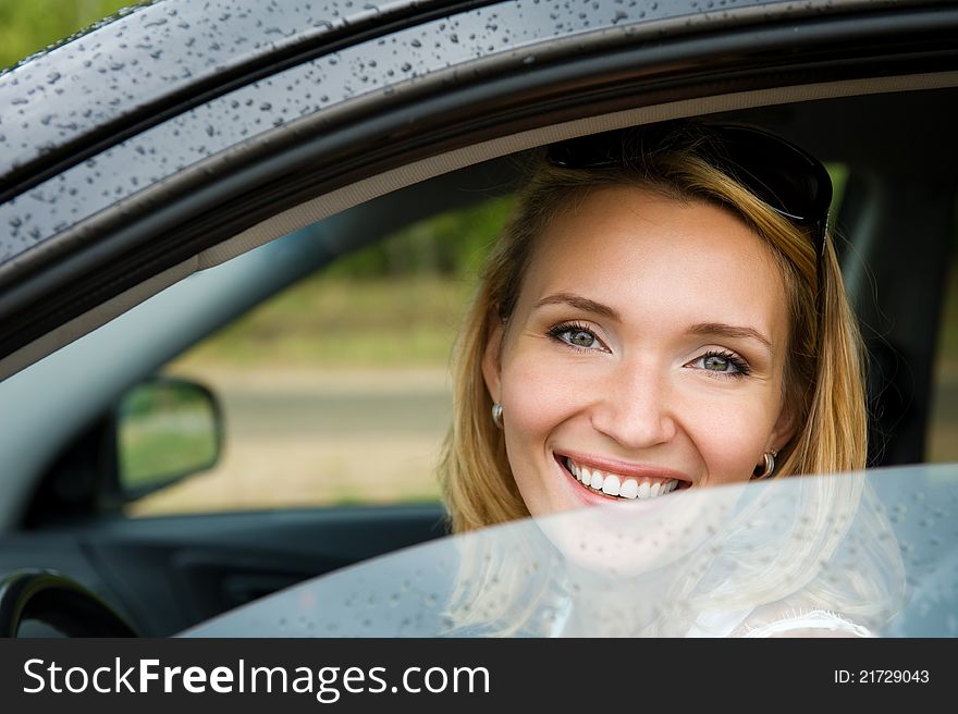 Portrait of attractive young smiling woman in the new car  - outdoors