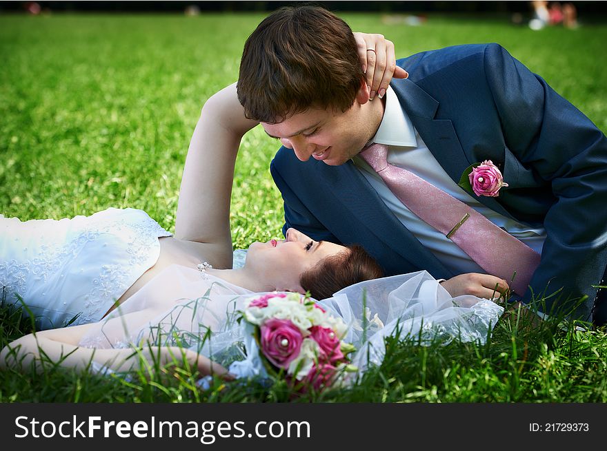 Happy bride and groom at wedding walk on grass in park