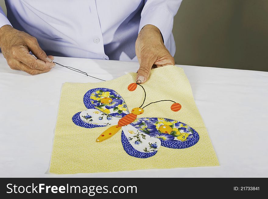 A woman chain stitching fabric to make butterfly squares. A woman chain stitching fabric to make butterfly squares.
