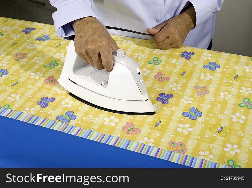 A woman irons colorful fabric to be used in making a pillow case. A woman irons colorful fabric to be used in making a pillow case.