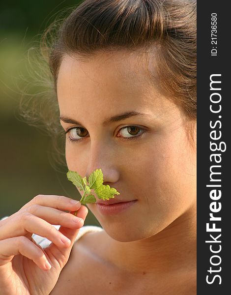 Beautiful young girl smelling melissa leaf