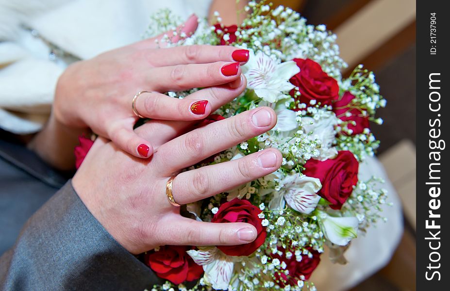 Hands of a newly-married couple lying on a wedding bouquet. Hands of a newly-married couple lying on a wedding bouquet