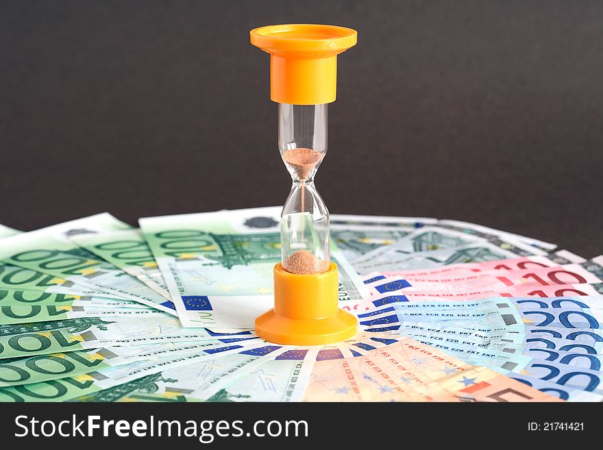 Time is money concept. Hourglass standing on european union currency background