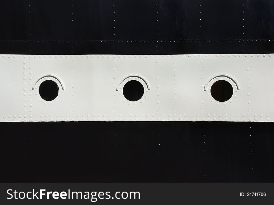 Three porthole window on a ship's hull. Black and white stripes with a round windows on board the ship with rivets. Three porthole window on a ship's hull. Black and white stripes with a round windows on board the ship with rivets.