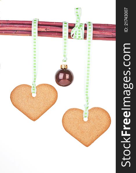 Homemade gingerbread hearts and christmas ball hanging from branches isolated over white background. Traditional christmas concept. Homemade gingerbread hearts and christmas ball hanging from branches isolated over white background. Traditional christmas concept.