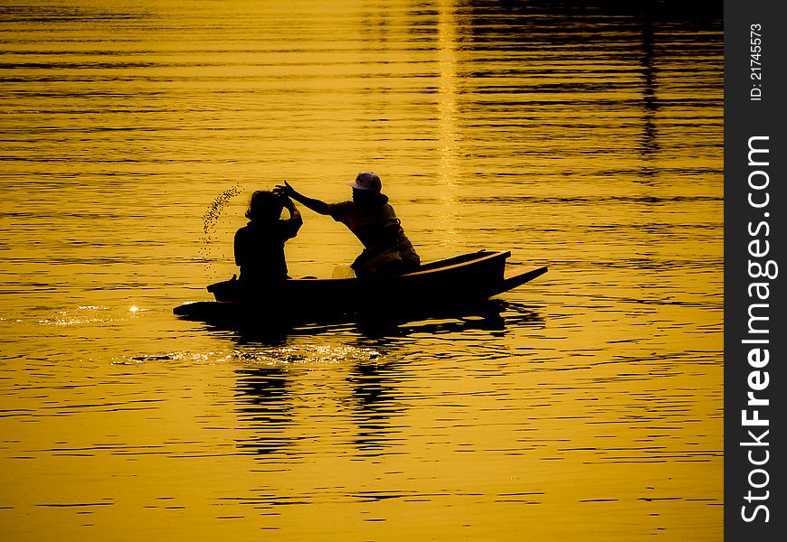 Two people in a boat with the golden light of sunset. Two people in a boat with the golden light of sunset