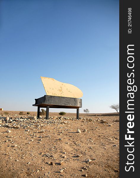 Piano in the desert sun by day