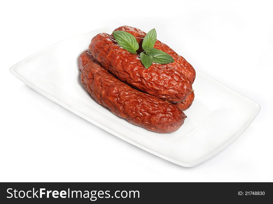 Venison sausage on a white plate with a mint leaf. Venison sausage on a white plate with a mint leaf